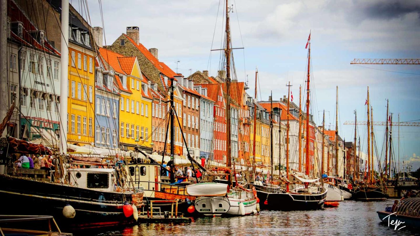 boats on the water next to a row of buildings
