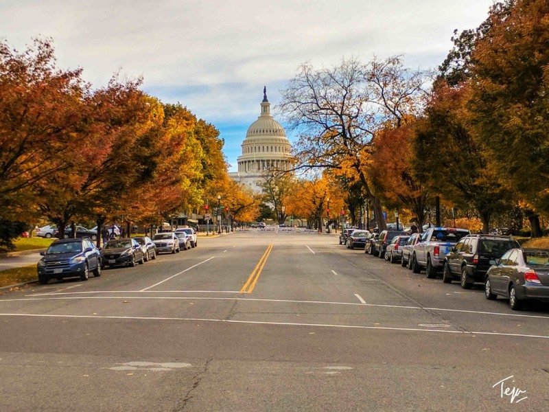 a street with cars parked in front of a capitol building