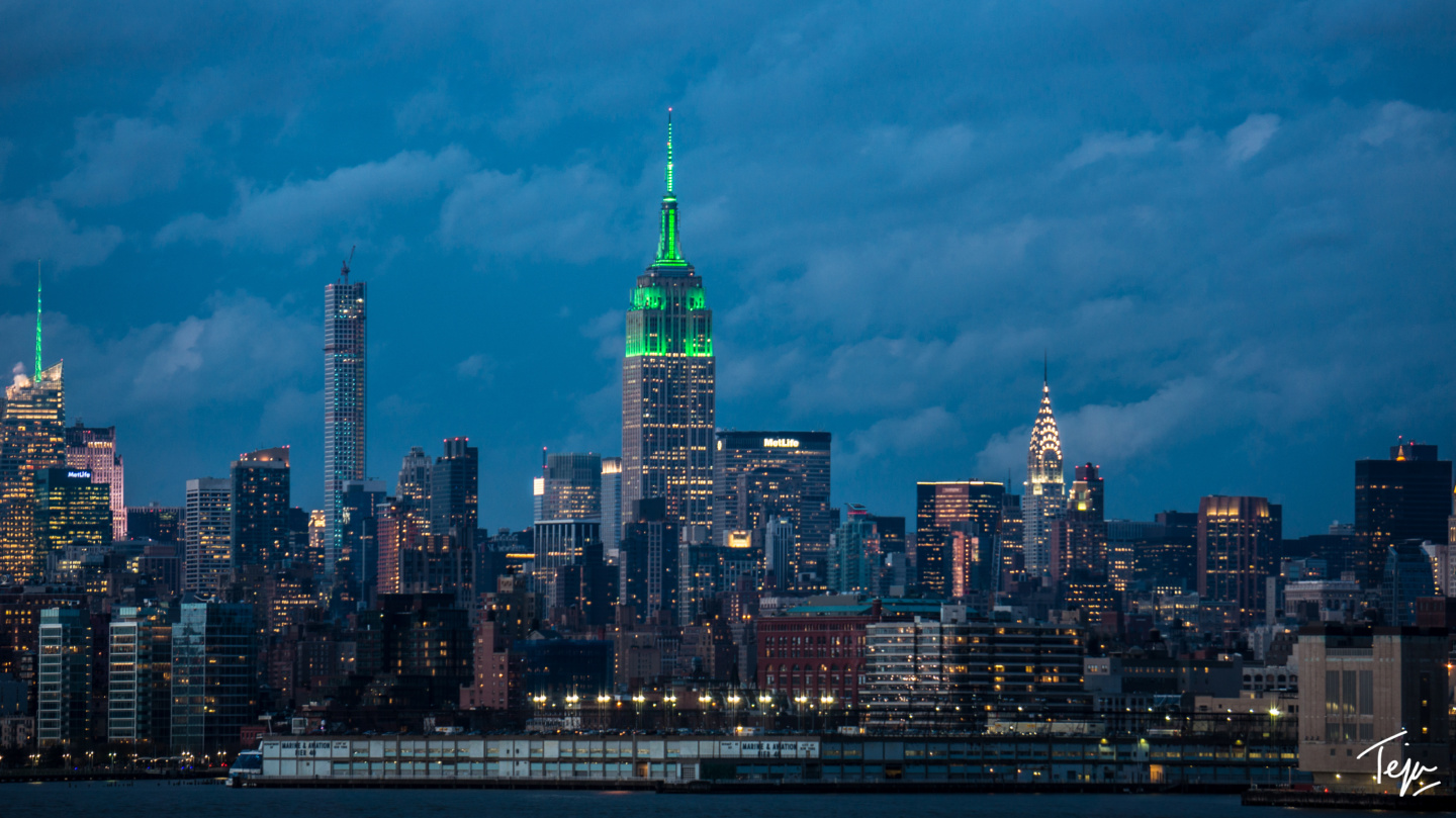 a city skyline with many tall buildings and a body of water