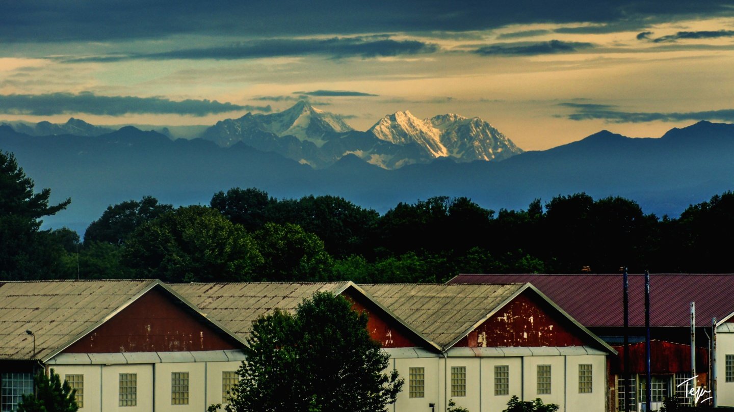 a group of buildings with trees and mountains in the background