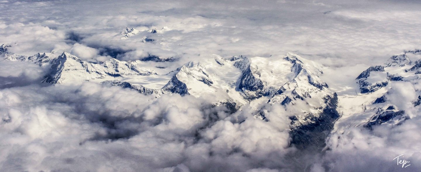 a snowy mountain tops with clouds