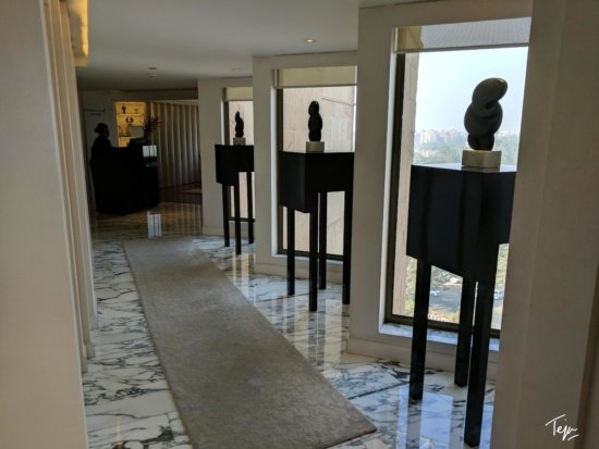a hallway with a marble floor and a marble floor with a white rug and a black sculpture on the side