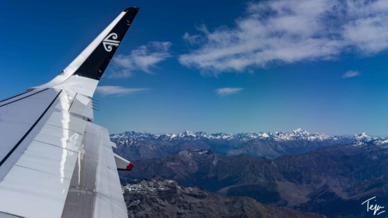 the wing of an airplane flying over mountains