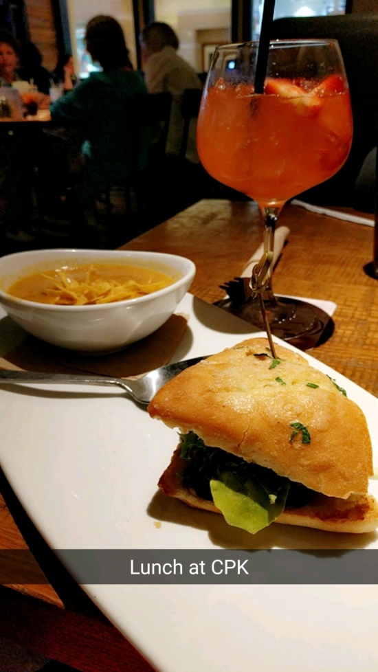 a sandwich on a plate with a glass of orange liquid
