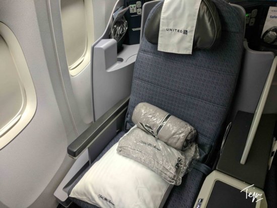a seat with a folded blanket and pillows on it
