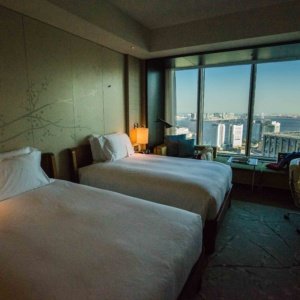 two beds in a room with a window and city view