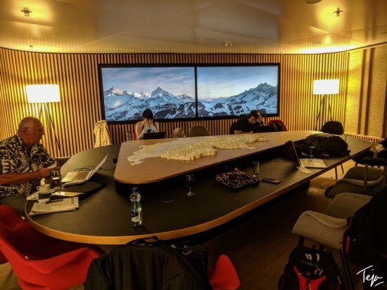 a room with a large table with a large screen and a large map