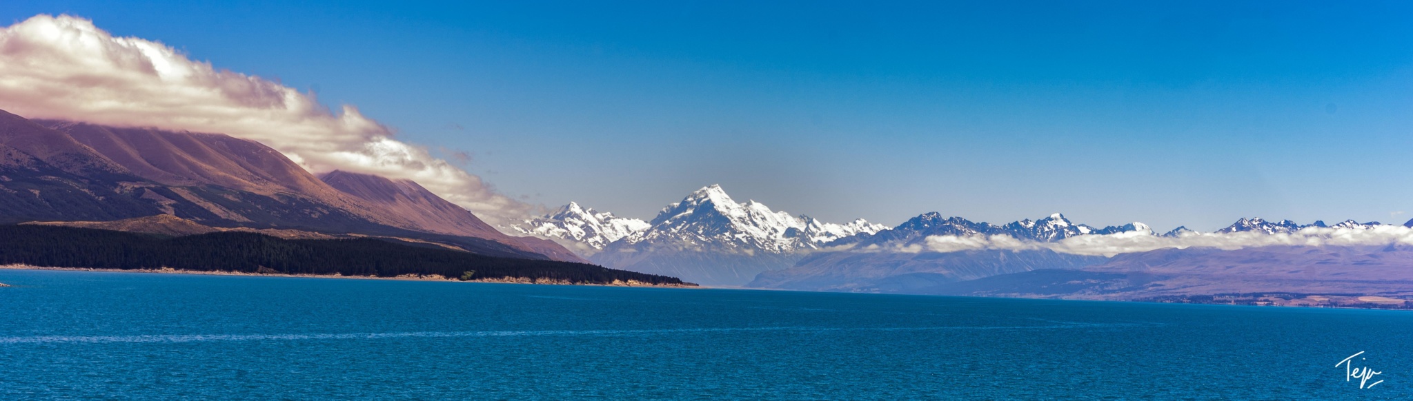 a body of water with snow covered mountains in the distance