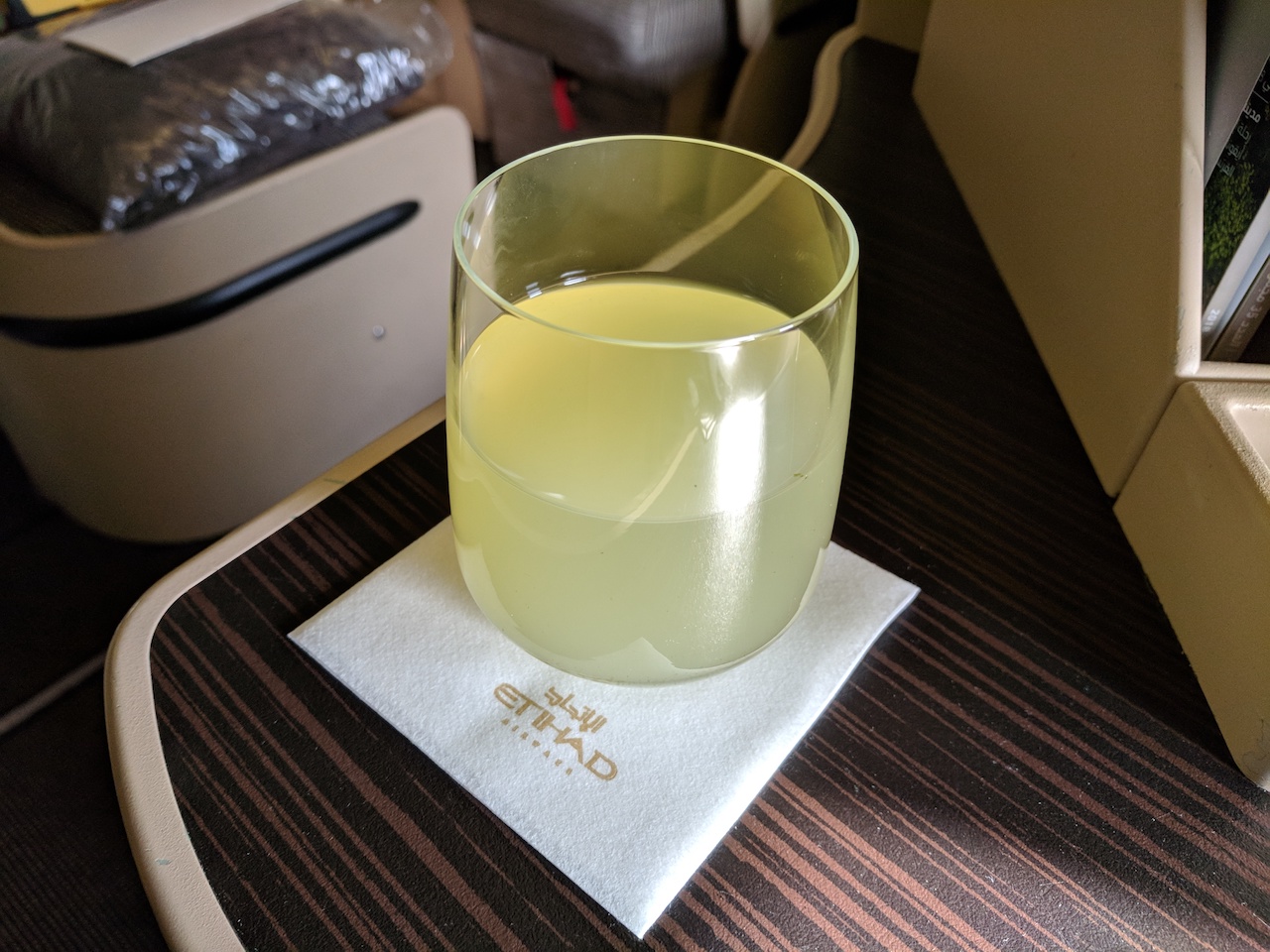 a glass of yellow liquid on a napkin