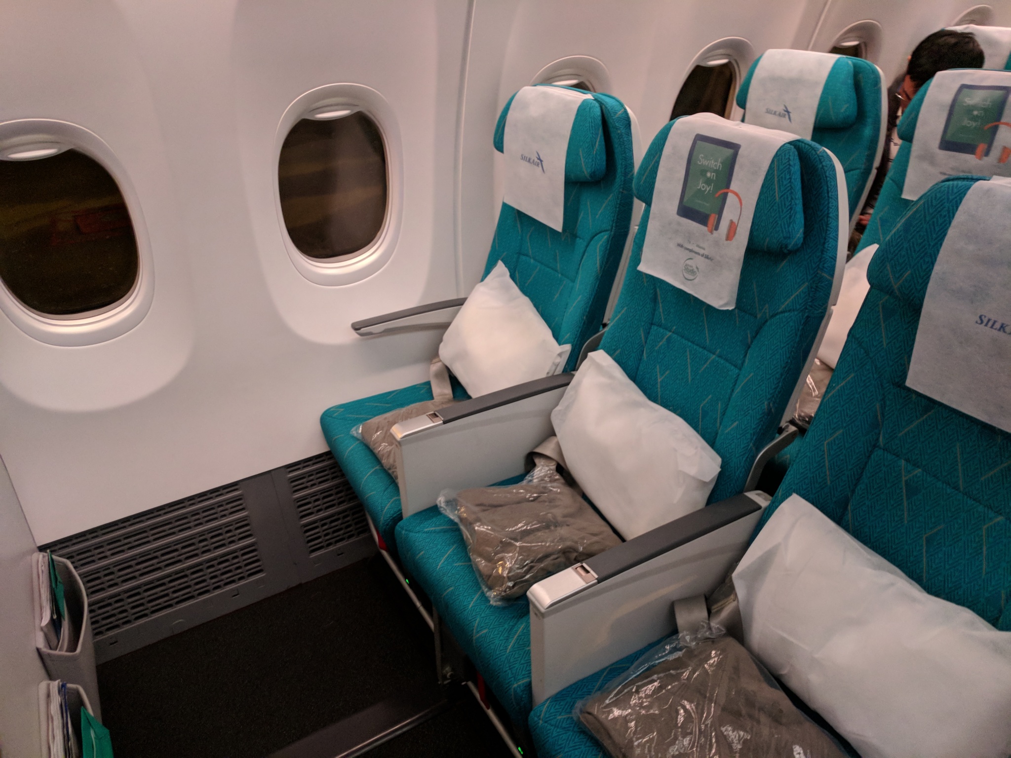a row of blue chairs with white pillows on the side of a plane