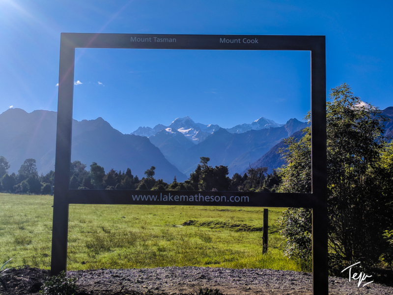 a sign in a field with mountains in the background