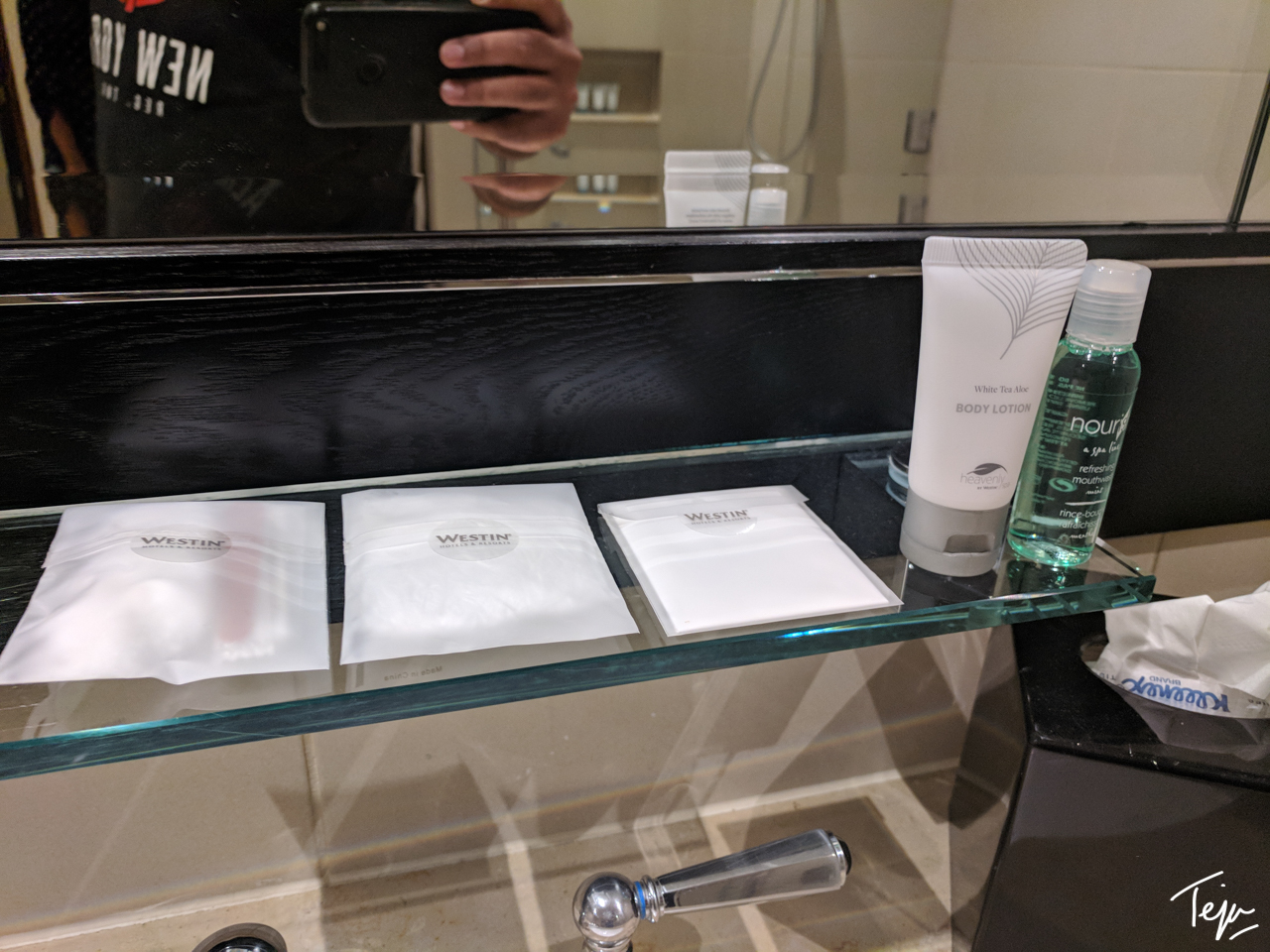 a bathroom shelf with a group of toiletries and a mirror