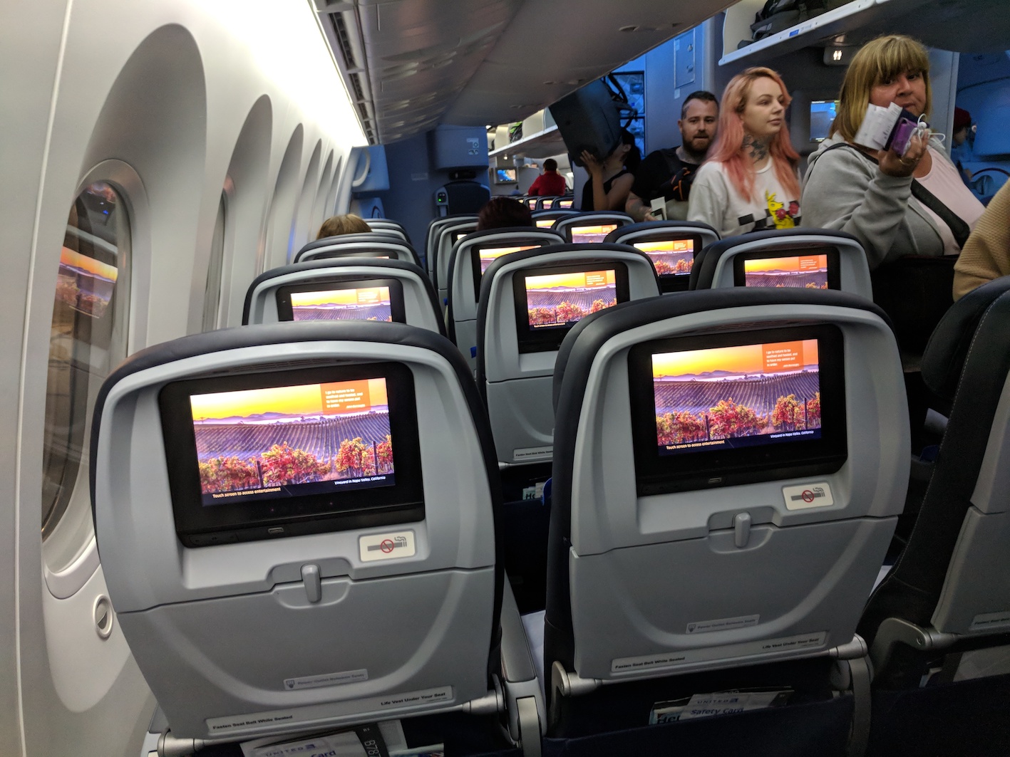 a group of people on an airplane with a television screen