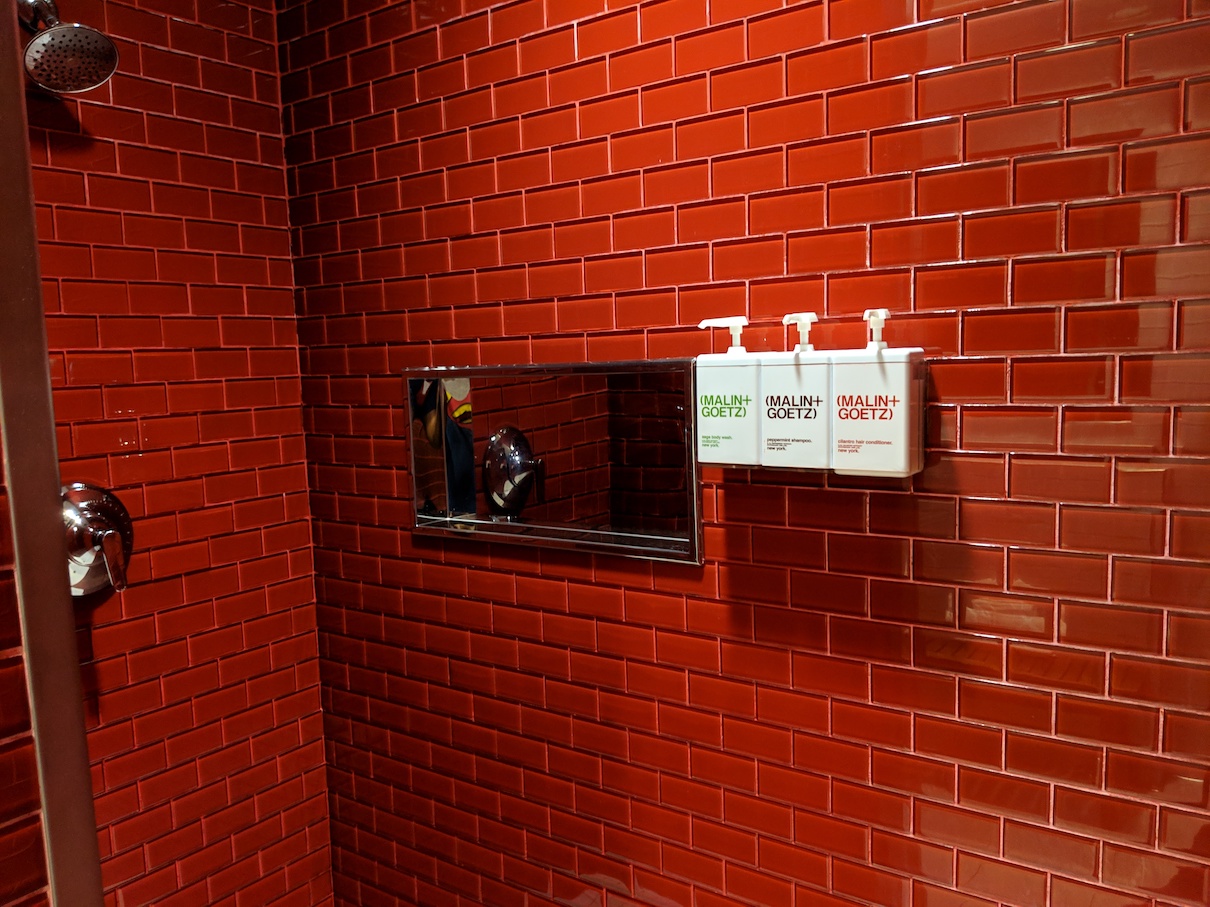 a red brick wall with a mirror and soap dispenser