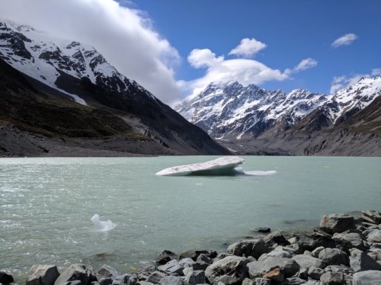 a glacier in a body of water with mountains in the background