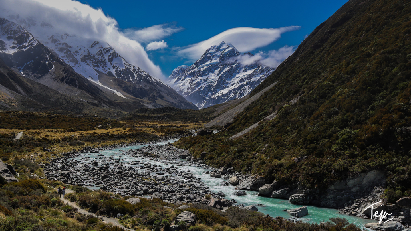 a river running through a valley with mountains in the background