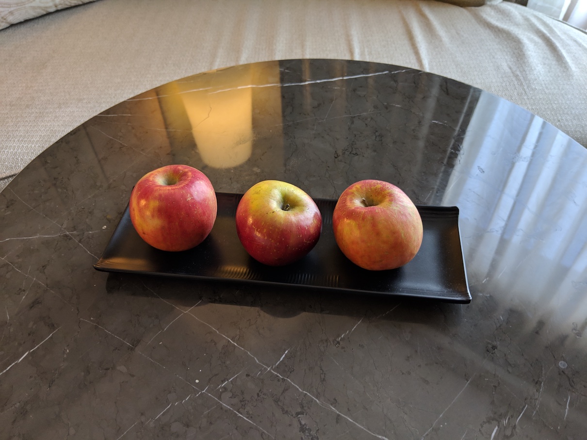 a group of apples on a black plate on a marble table