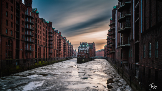 a river between buildings with a cloudy sky