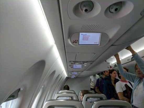people in an airplane with a screen on the ceiling