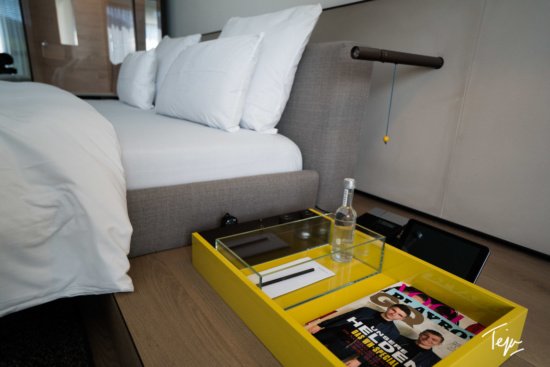 a yellow tray with a magazine and a bottle on a table next to a bed