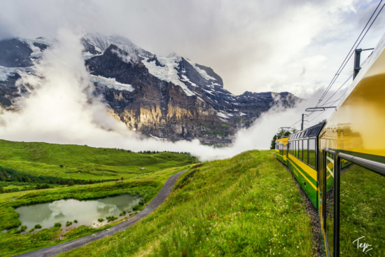 a train going down a hill with mountains in the background