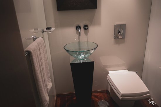 a bathroom with a glass sink and a toilet