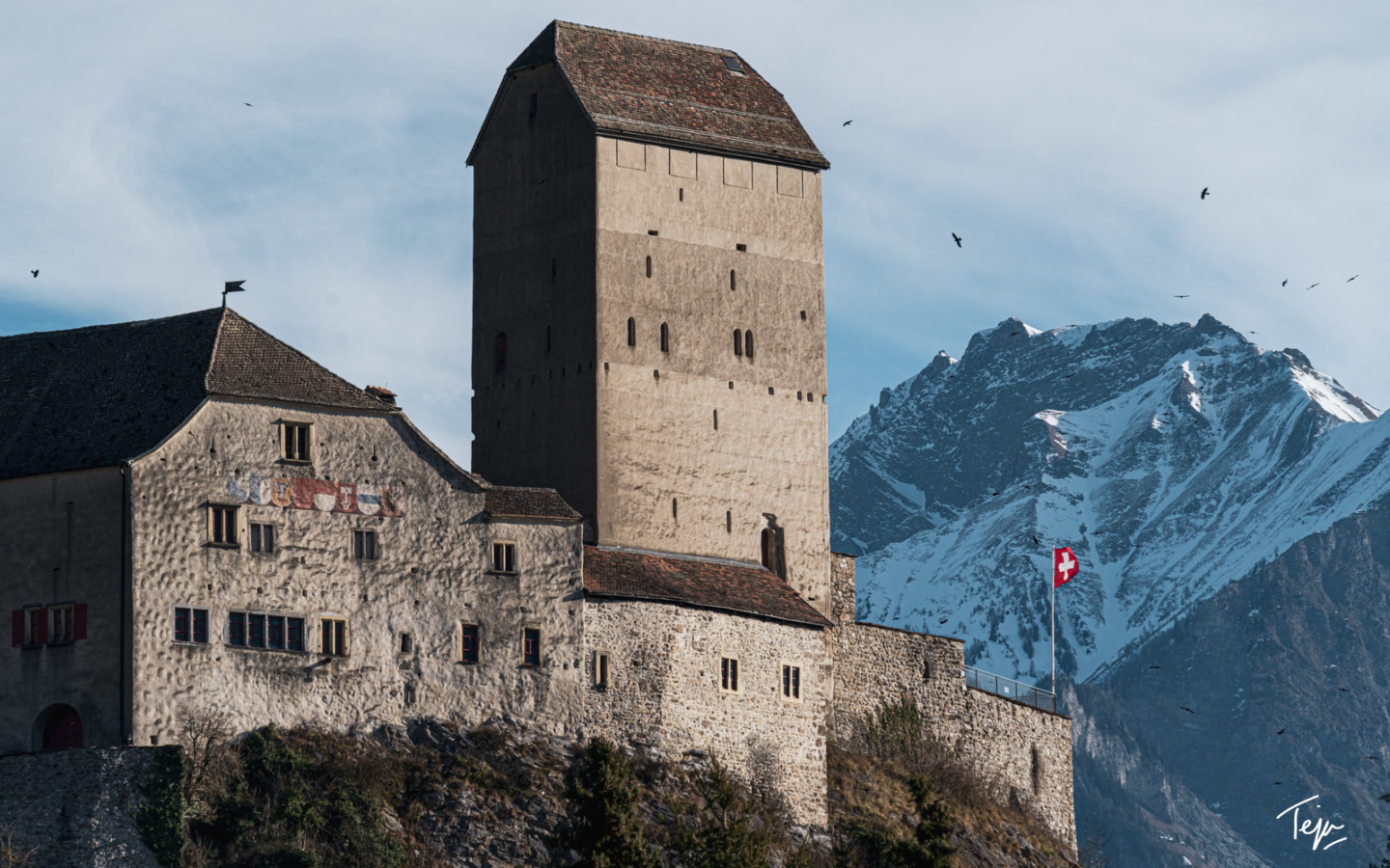 a stone building on a hill with a flag on it
