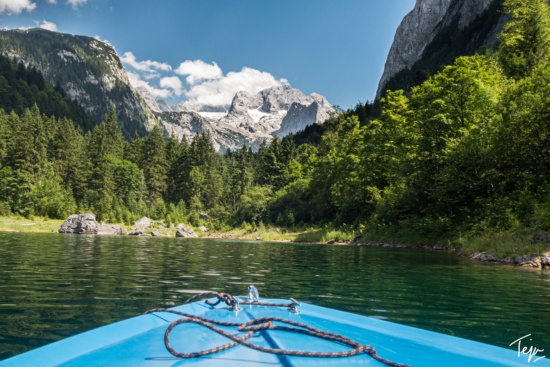 a boat on a lake surrounded by trees and mountains