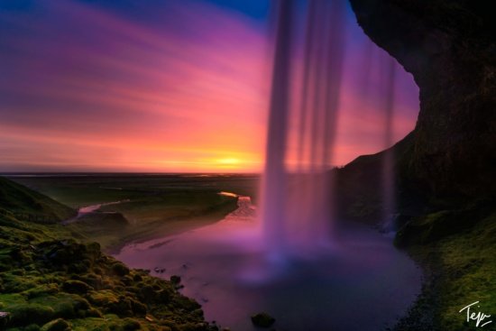 a waterfall with a sunset behind it