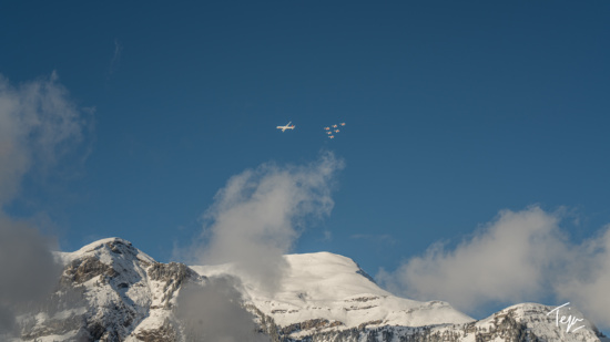 a group of airplanes flying in the sky over a snowy mountain