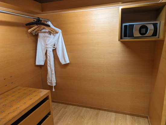 a white robe from a rack in a room with a wood wall and a microwave