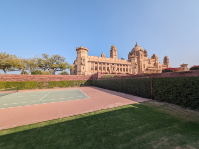 a tennis court in front of a large building with Red Fort in the background