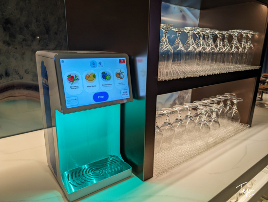 a machine with a screen next to a row of wine glasses