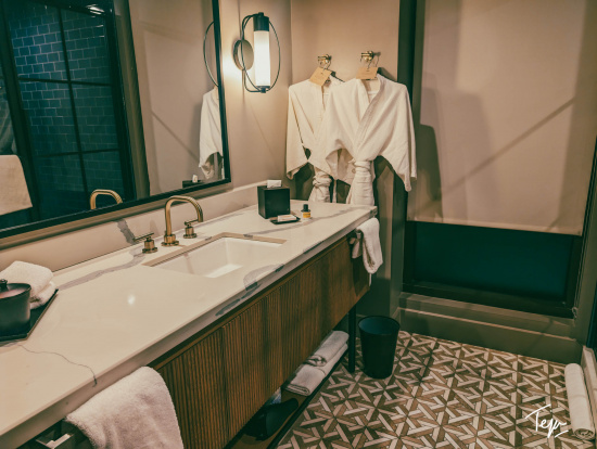 a bathroom with a mirror and white bathrobes