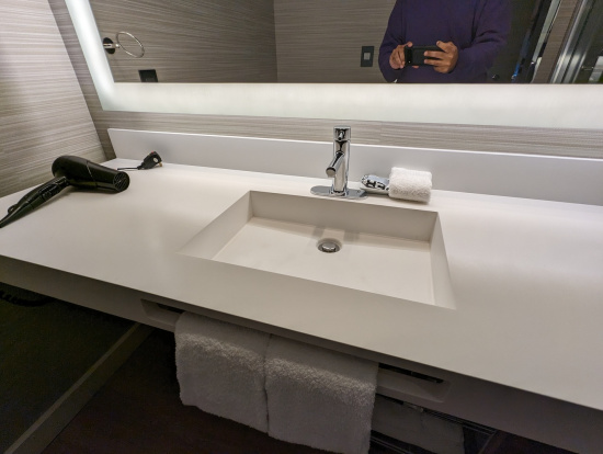 a bathroom sink with a mirror and a hand holding a phone