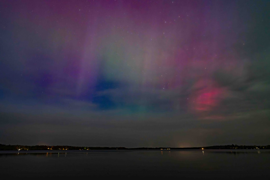 a body of water with a purple and green sky