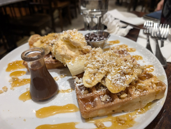 a plate of waffles with toppings and chocolate sauce