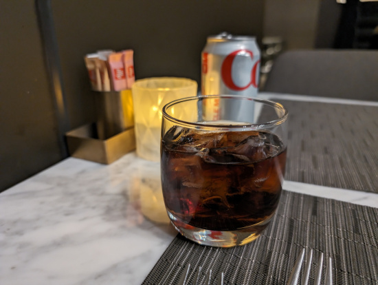 a glass of liquid with ice and a can of soda