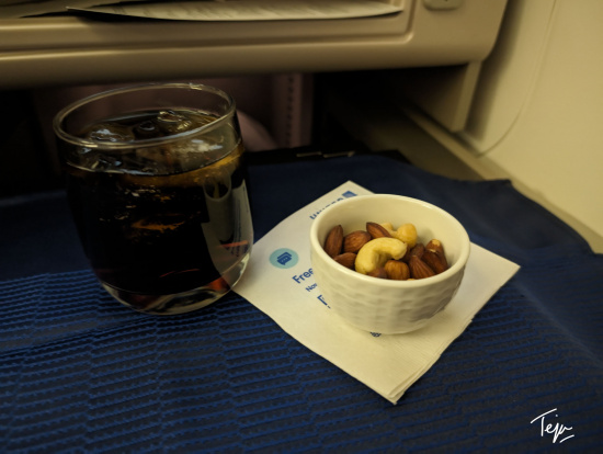 a bowl of nuts and a glass of liquid on a table